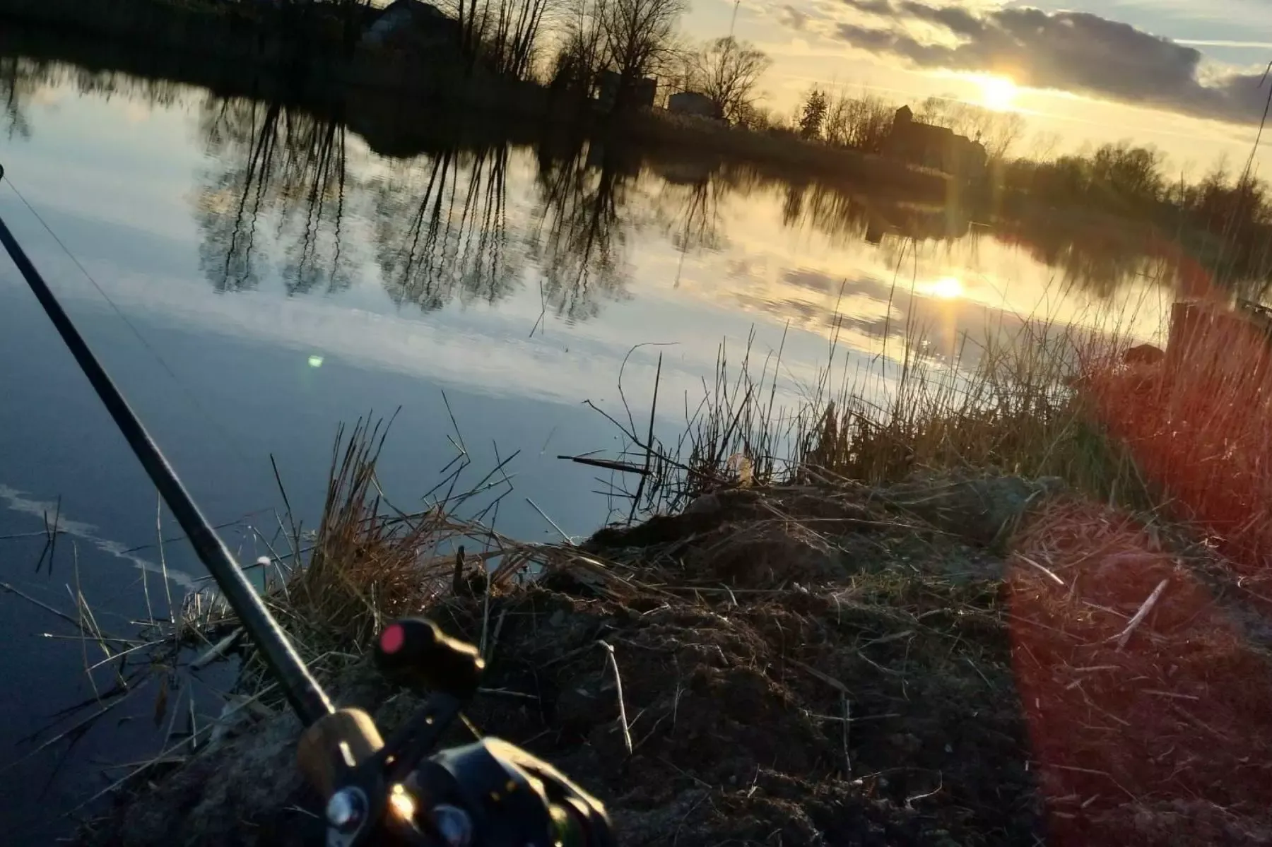 Sonnenuntergang am Łowisko Małe Samsieczno mit einer Spinnrute am Ufer